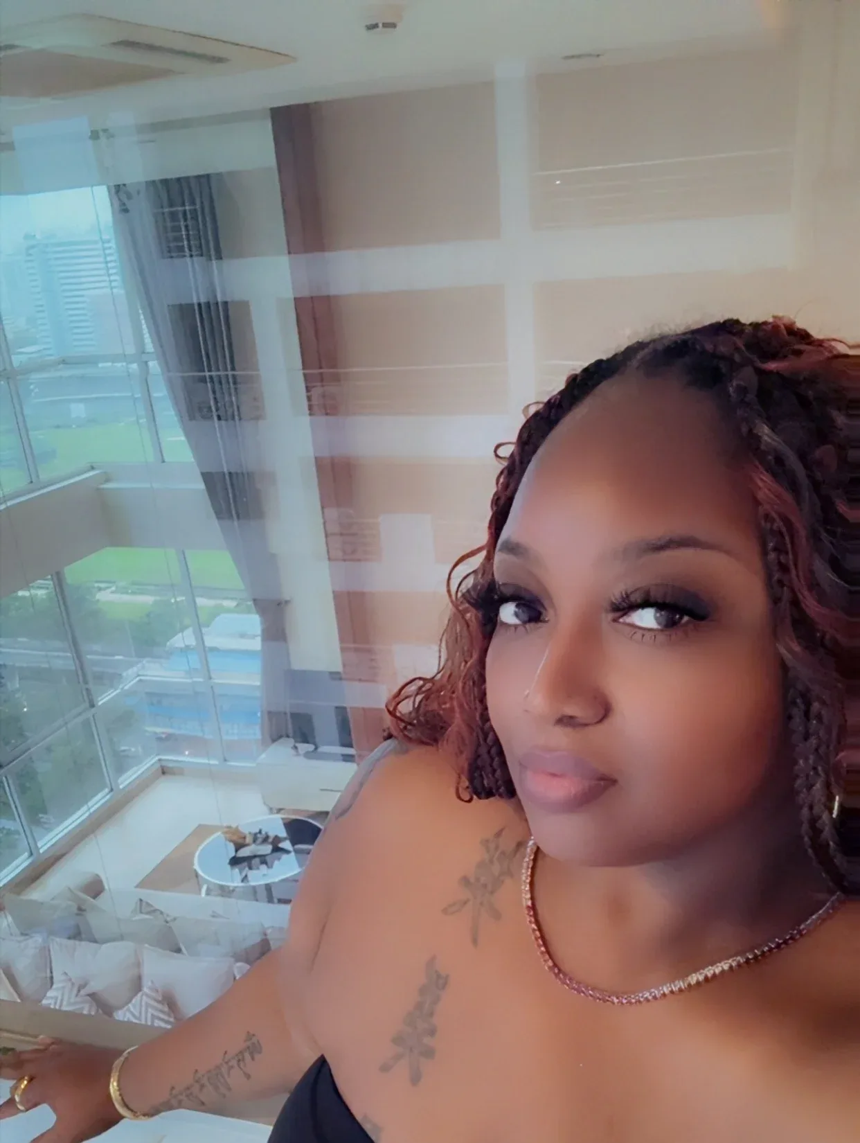 Charlene smiling beside floor-to-ceiling windows in a high-rise living room