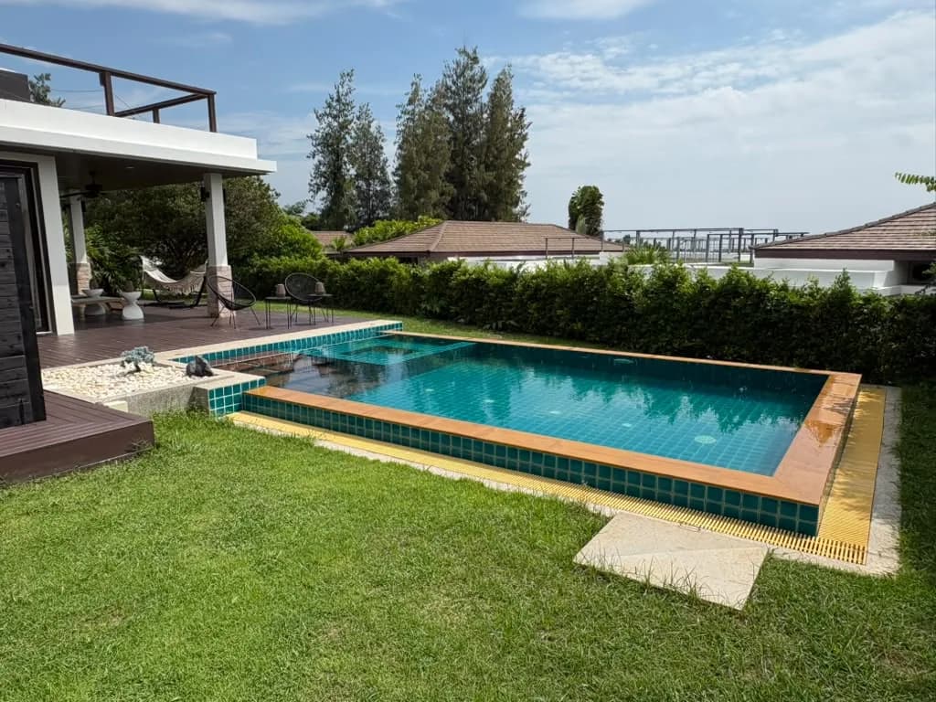 Private pool beside a shaded deck and lawn, with hills beyond