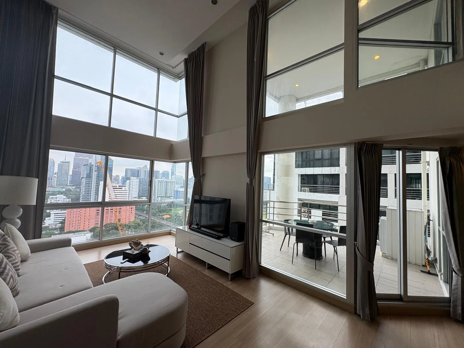 Double-height living room with floor-to-ceiling windows over the Bangkok skyline